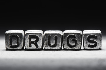 The word drugs on metal cubes on a black background