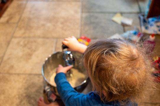 Caucasian Boy With Blonde Hair Stirring Batter In A Mixing Bowl