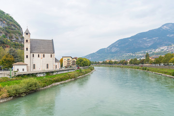 Fototapeta na wymiar View to the church St Apollinare in Trento, Italy. The river etsch in the center.