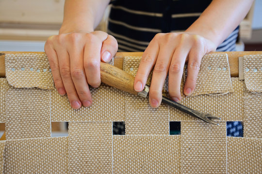Woman hands in upholstery workshop. Removing old tacks. Working with upholstery tools. Nail remover. Tack lifter removing old nails from wooden construction.