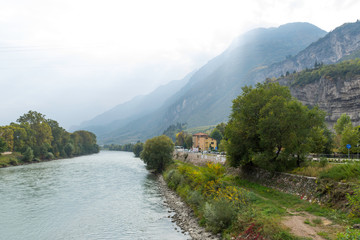 Colorful apartment buildings along a public square. In the foreground are plane trees. The houses are old but well preserved.