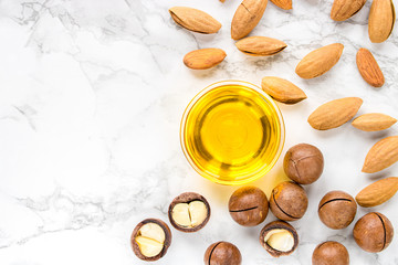 almond and macadamia oil on a white marble background. The concept of healthy vegan food and natural cosmetics. Flat lay.