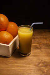 Glass of freshly squeezed orange juice with straws and slices of orange