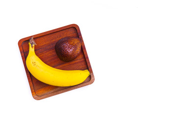 Yellow ripe bananas and salak fruit on a wooden board, isolated from a white background and copy space
