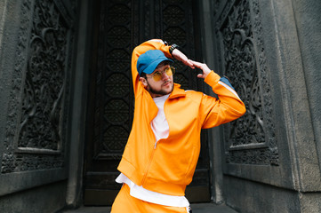 Stylish young hip hop dancer showing a dance performance on the street against the backdrop of old...