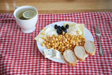 breakfast set of fried egss with lentils, olives, blue cheese and green tea with lemon