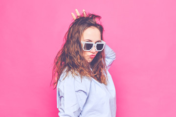 Stylish caucasian girl in a pale blue t-shirt and 8-bit glasses. Screaming at the camera. Toned.