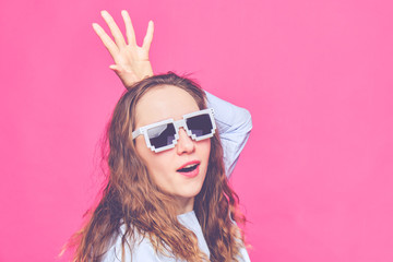 Stylish caucasian girl in a pale blue t-shirt and 8-bit glasses. Screaming at the camera and portray the queen. Toned.