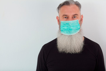 Portrait of middle-aged bearded man in a medical mask. A concept of the danger of coronavirus for the elderly.