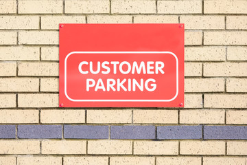 Customer parking only sign on brick wall at bank shop car park