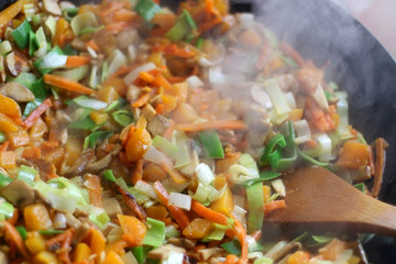 Stir- fry vegetables and portobello mushrooms in a wok. Selective focus.