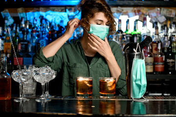 bartender girl puts on medical mask at bar