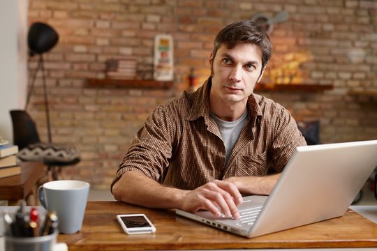 Home office - Busy man working at desk on laptop computer