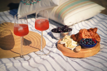summer breakfast with croissants, cheese, cocktails and fruits on the beach
