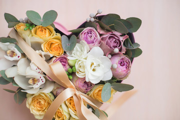 Stylish flowers arrangement in a pink hatbox. White orchid, purple and yellow roses with bunch....