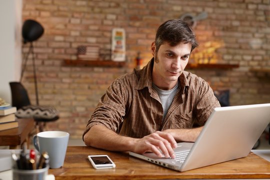 Home office - Casual man using laptop working at home 