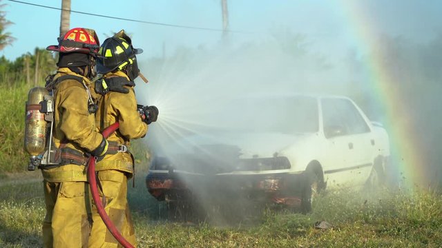 firefighter using spraying water to the fire buring in car accident
