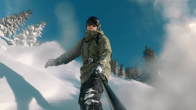 Happy snowboarder snowboarding down the slope on a powder snow day. A sunny winter day with blue sky.  Perfect travel destination, extreme sports. 