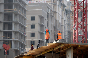 Builders work at the construction site, installation of formwork for walls. Workers on background...