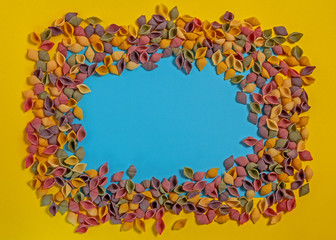 Pasta Conchiglie Rigate, mix of colorful uncooked shells with spinach and tomatoes. Textured Italian food background concept. Top view flat lay close up copy space