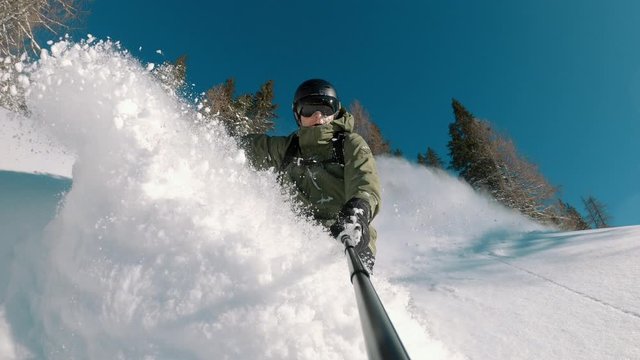 Happy snowboarder snowboarding down the slope on a powder snow day. A sunny winter day with clear sky.  Perfect travel destination, extreme sports, beautiful landscape and nature.