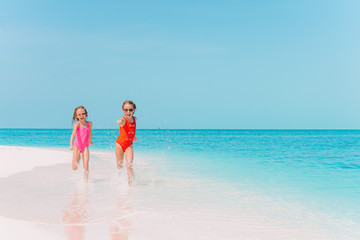 Little happy funny girls have a lot of fun at tropical beach playing together.