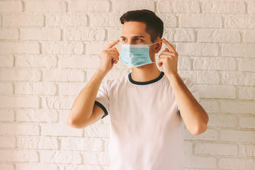 Portrait of young confident man putting on protective mask on face. Doctor professional wearing...
