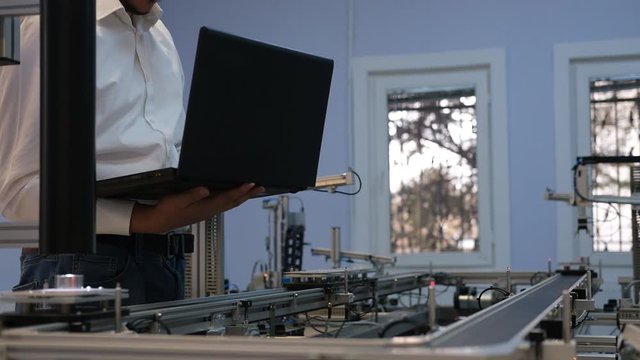 Industry 4.0 concept; Engineer is working on laptop to program smart factory prototype's automation. automated car on production line, artificial intelligence in smart manufacturing.