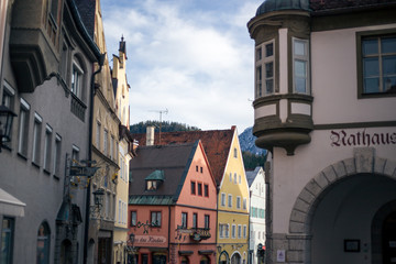 Alpine mountains with snowy peaks. Old european houses. Blue sky with clouds.