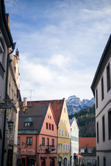 Fototapeta premium Alpine mountains with snowy peaks. Old european houses. Blue sky with clouds.