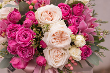 Woman florist making a lovely Flower composition in round hat box of  roses in girl hands.