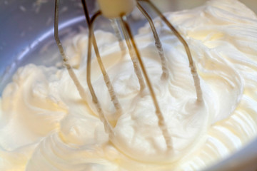 Mixing white egg cream in bowl with electric mixer, baking cake