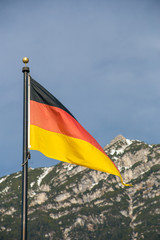 Wawing German flag against mountains of rocks and blue sky