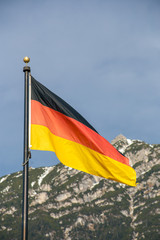 Wawing German flag against mountains of rocks and blue sky