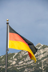 Wawing German flag against mountains of rocks and blue sky