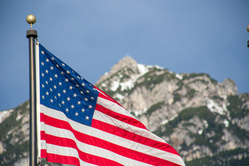 Wawing American flag against mountains of rocks and blue sky