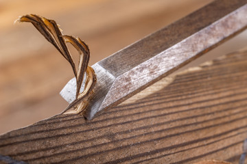 Chisel work in wood and raw wood shavings. Tools and accessories in a carpentry shop.