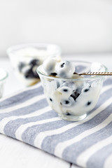 Yogurt with honey and fresh bilberries on bright background. Close up.