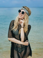 Young attractive girl in hat and glasses on the shore of the blue sea enjoys, Thailand