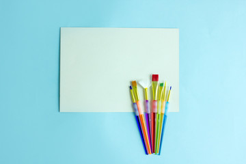 Colored paint brushes on a blue background, copy space