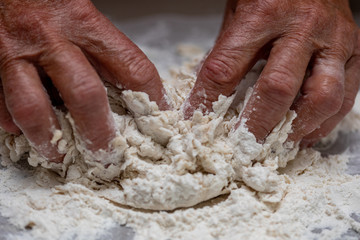 Elderly woman miking dough with her hands