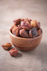Homemade dried apricots in wooden bowl on wood textured background. Copy space. Superfood, vegan, vegetarian food concept. Macro of dried apricot, selective focus. Healthy snack