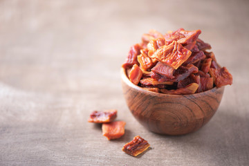 Dried papaya slices in wooden bowl on wood textured background. Copy space. Superfood, vegan, vegetarian food concept. Macro of papaya texture, selective focus. Healthy snack