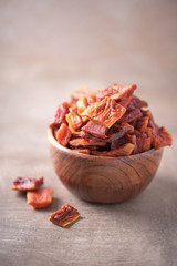 Dried papaya slices in wooden bowl on wood textured background. Copy space. Superfood, vegan, vegetarian food concept. Macro of papaya texture, selective focus. Healthy snack