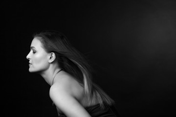 Classic black-and-white dramatic portrait of an adult blonde woman in Studio on black background.