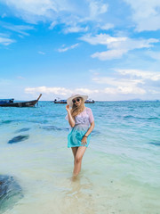 A young attractive girl in a hat and glasses on the shore of the blue sea enjoys a vacation and travel, bounty island Thailand