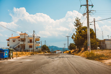 Fototapeta na wymiar Empty rural road going through prairie under cloudy sky in Greece, Corinth. Vintage style processing image.