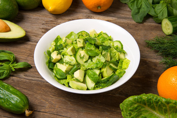 Salad with citrus vinaigrette, avocado cucumber green beans and romaine salad in an bowl on a rustic wooden table. Selected focus.