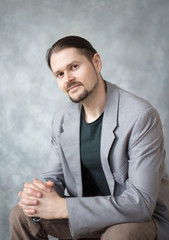 Portrait of a young man in a business jacket on a gray background in the studio.