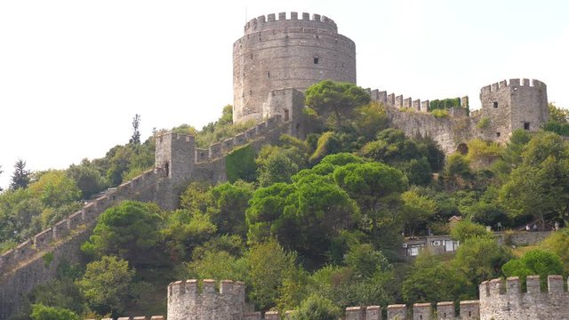 Old ancient historic castle in the woods  Panning shot of an old brick made fortress and high guard towers and flags floating above no people around in Asian Istanbul Turkey